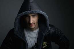 Portret dramatic bărbat cu glugă, expresie intensă, hanorac Adidas, fundal întunecat, fotografie de studio