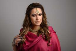 Portret studio femeie în ținută indiană tradițională, sari roz, bijuterii aurii, machiaj accentuat, henna pe mâini