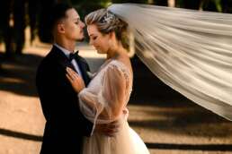 Fotografii de nuntă în București – cuplu în ipostază romantică, mireasă cu voal lung și mire în costum elegant, lumină caldă de apus