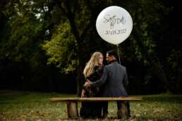 Cuplu logodit pe o bancă în parc ținând un balon Save The Date, fotografie logodnă, fotograf nunta București