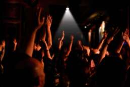 Public entuziast cu mâinile ridicate la un concert live în cadrul unei petreceri corporate, lumină de scenă focalizată în fundal