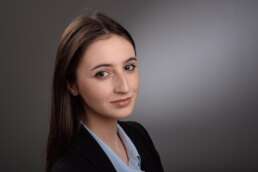 Portret profesional al unei tinere în costum business, cu zâmbet discret și privire calmă